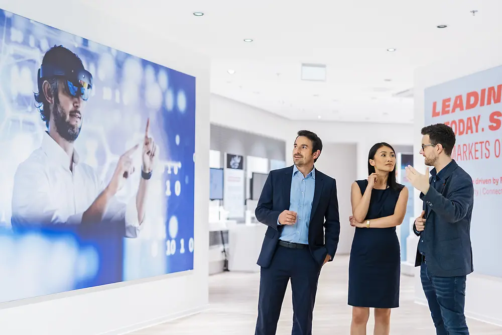 A customer experience tour guide presents Henkel Adhesive Technologies portfolio to two customers at the Inspiration Center Düsseldorf.